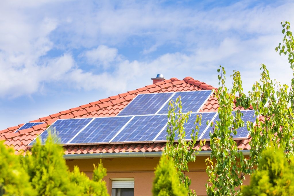 Solar panel cells on the roof of a new house agains blue sky.