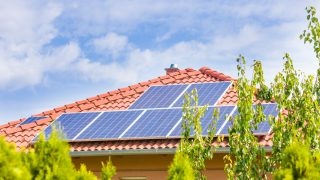 Solar panel cells on the roof of a new house agains blue sky.